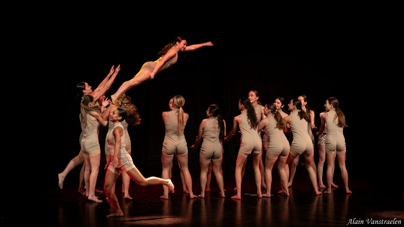Une danseuse portée en vol au-dessus du groupe, le reste de la troupe alignée en fond